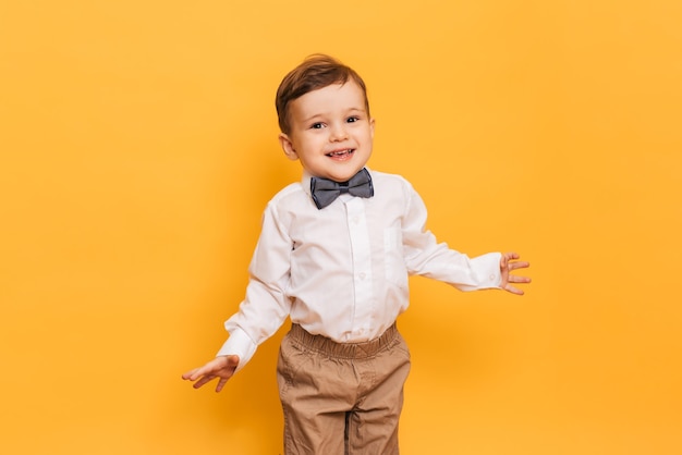 Uma foto de estúdio de um menino bonitinho fazendo careta fica em um fundo amarelo. Garoto engraçado