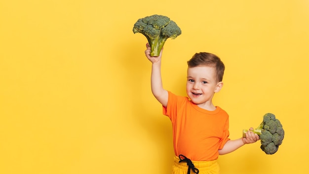 Uma foto de estúdio de um menino segurando um brócolis fresco.