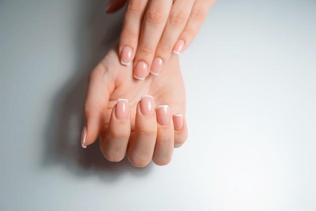 Uma foto de mãos mostrando suas unhas, unhas francesas