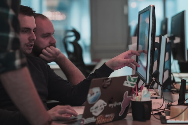 Uma foto de três homens olhando atentamente para um computador enquanto estão sentados em um foco seletivo de escritório moderno