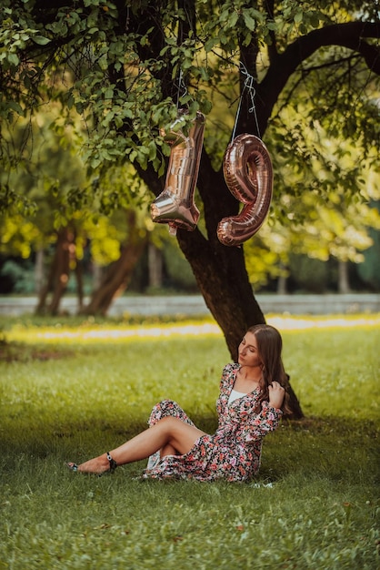 Uma foto de uma adolescente sendo fotografada ao lado de um número de aniversário no parque