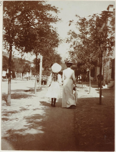 uma foto em preto e branco de duas mulheres em um vestido com um chapéu