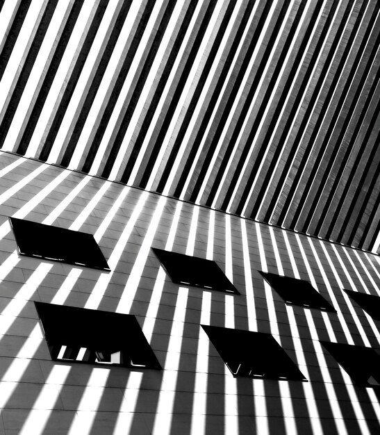 Uma foto em preto e branco de um prédio com janelas e linhas na parede.