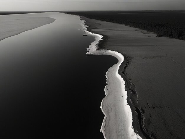 uma foto em preto e branco de uma praia com uma onda na água