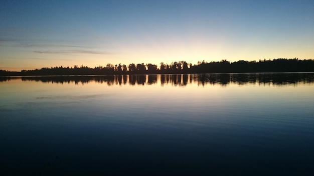 Uma foto panorâmica de um lago calmo ao pôr-do-sol