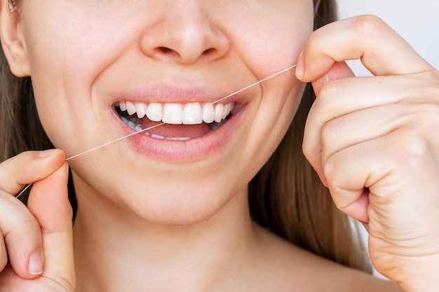 Uma foto recortada de uma jovem loira caucasiana passando fio dental nos dentes após a refeição Conceito de odontologia
