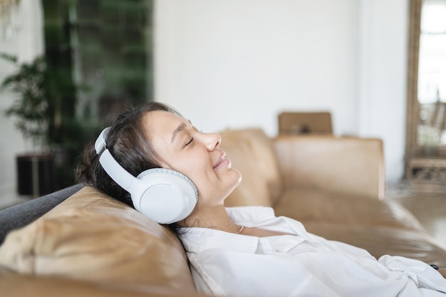 Uma freelancer feminina ouve música calma com fones de ouvido usando um novo equilíbrio e harmonia de aplicativos