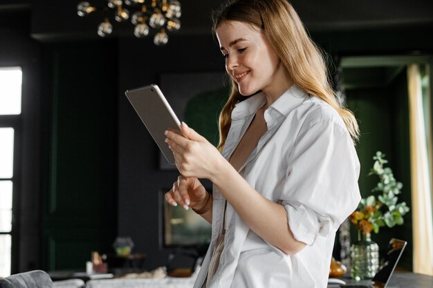 Uma freelancer feminina trabalha em um local de trabalho de hotel usa um tablet se comunicando com um cliente