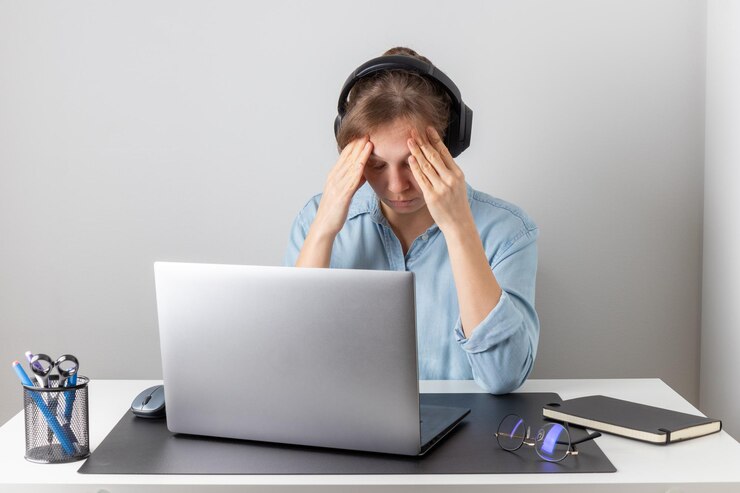 Uma freelancer sobrecarregada de trabalho está cansada e estressada atrás de seu laptop Exaustão e esgotamento problema de trabalho remoto Mulher luta com fadiga e estresse relacionado ao trabalho