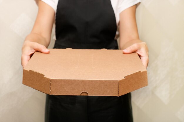 uma funcionária de um café segura uma caixa com pizza pronta