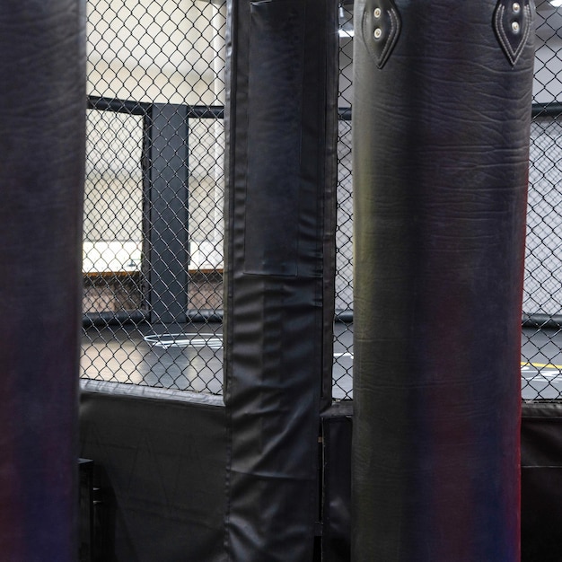 Uma gaiola de kickboxing octogonal com sacos de boxe no complexo esportivo