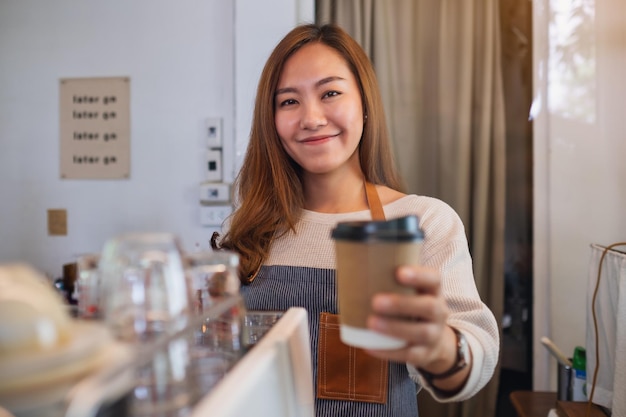 Uma garçonete segurando e servindo copos de papel com café quente para um cliente no café