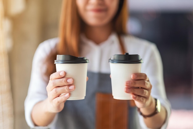 Uma garçonete segurando e servindo dois copos de papel com café quente em um café