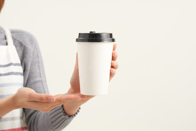 Uma garçonete segurando e servindo um copo de papel com café quente em um café