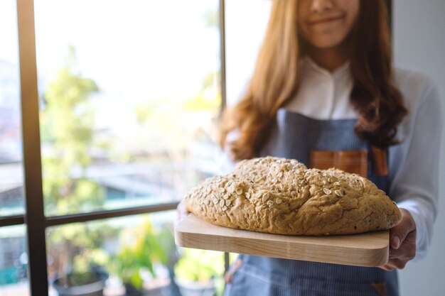 Uma garçonete segurando e servindo um pedaço de pão integral