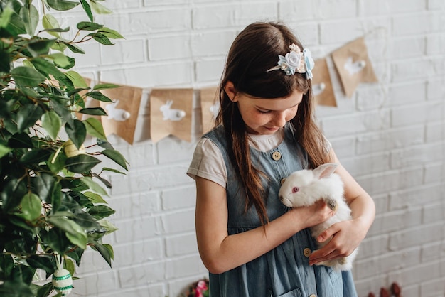 Foto uma garota abraça um coelho branco fofo em casa uma garota com um coelho um coelho de estimação uma garota abraça um coelho branco no estúdio