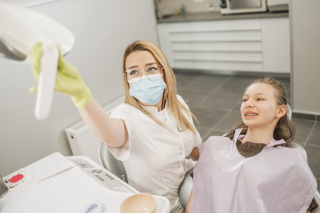 Uma garota adolescente, tendo os dentes verificados pelo dentista na clínica odontológica.