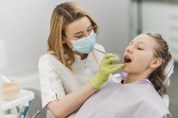 Uma garota adolescente, tendo os dentes verificados pelo dentista na clínica odontológica.