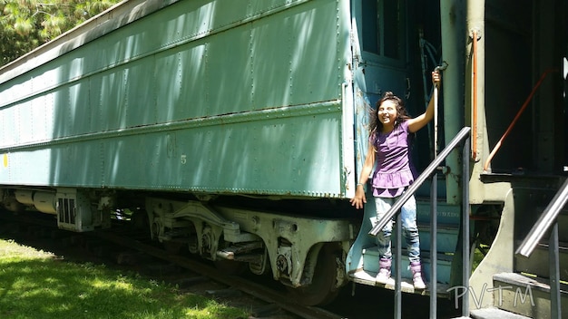 Foto uma garota alegre de pé no comboio.