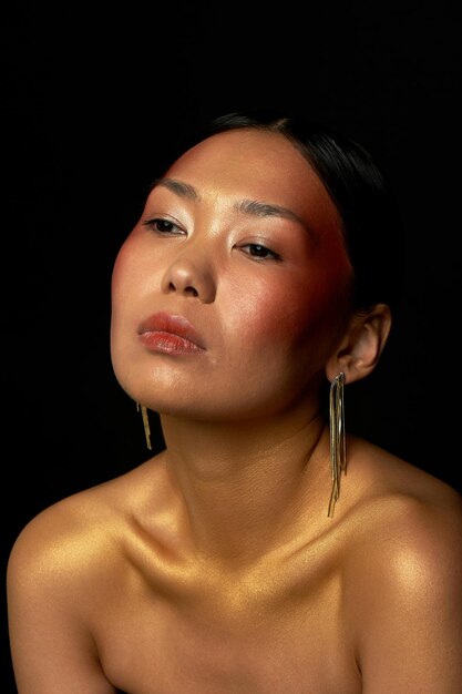 Uma garota asiática em um fundo preto no estúdio Ouro Finas clavículas Brincos longos de ouro O reino da beleza e do perfume