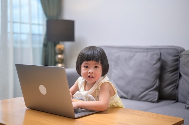 Uma garota asiática feliz usando laptop para estudar online via internet em casa. Conceito de e-learning