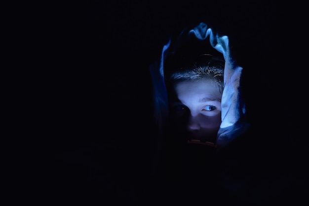 Uma garota assustada com uma luz deitada debaixo de um cobertor