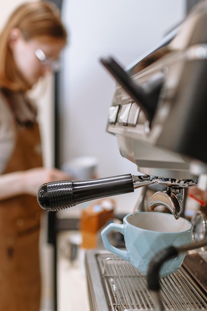 Foto uma garota barista derramando café de uma máquina de café em uma xícara café