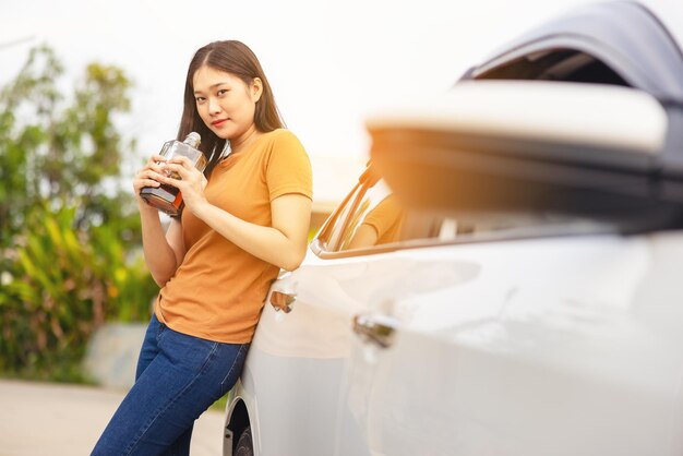 Uma garota bêbada está ao lado de seu carro com uma garrafa de álcool nas mãos. Uma mulher bebendo uísque.