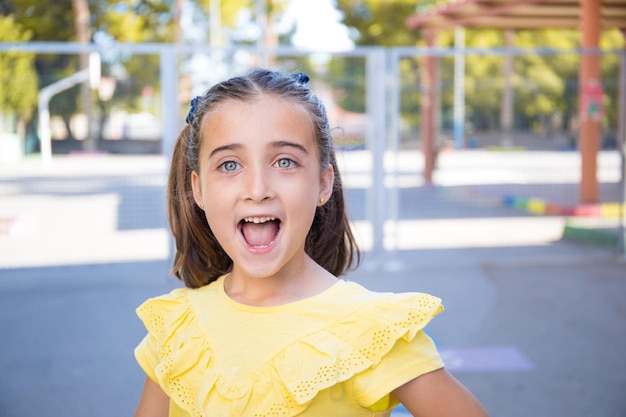 Uma garota bonita e de olhos claros em uma camiseta amarela está muito feliz em voltar para a escola.