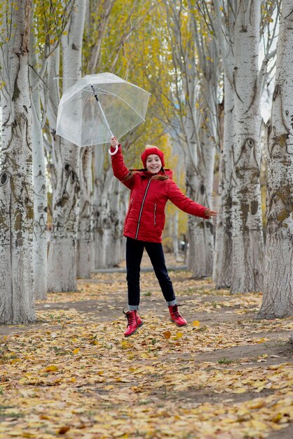 Uma garota caminha e brinca com um guarda-chuva transparente no parque Autumn Atmosther