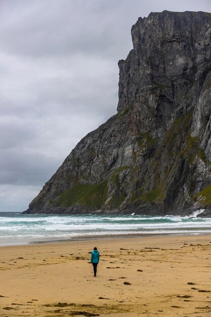 uma garota caminha sozinha na famosa praia kvalvika nas ilhas lofoten na noruega a famosa praia