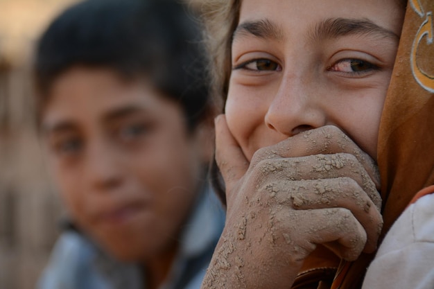 Uma garota com as mãos na boca está coberta de lama.