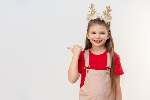 Uma garota com chifres de veado na cabeça e com uma roupa de Natal aponta o dedo para o anúncio.