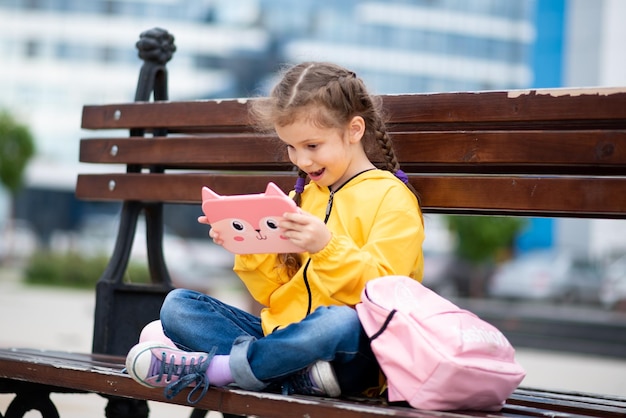 Uma garota com computador tablet Publicidade de novo aplicativo educacional de gadget As crianças usam tecnologia