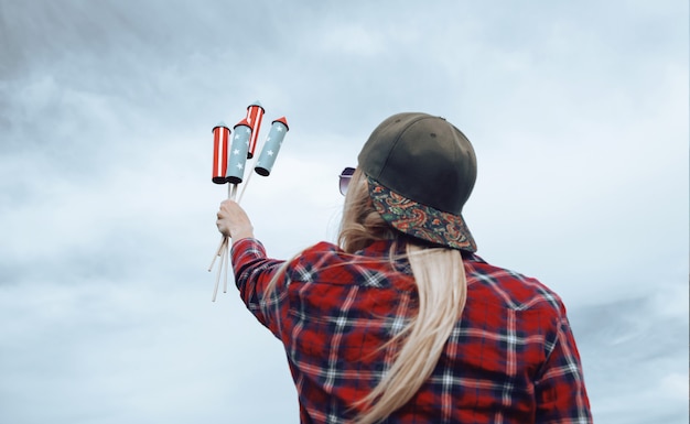 Uma garota com fogos de artifício nas mãos está se preparando para lançar mísseis em homenagem à celebração do Dia da Independência em 4 de julho