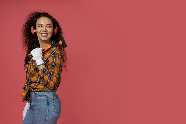 Uma garota com fones de ouvido de construção e com um martelo nas mãos