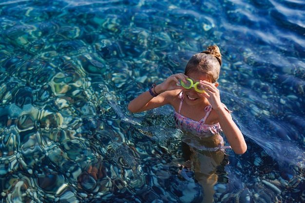 Uma garota com óculos de natação está prestes a mergulhar em águas claras