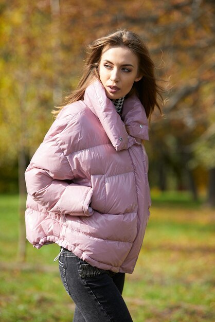 Uma garota com roupas de marca está caminhando em um parque de outono