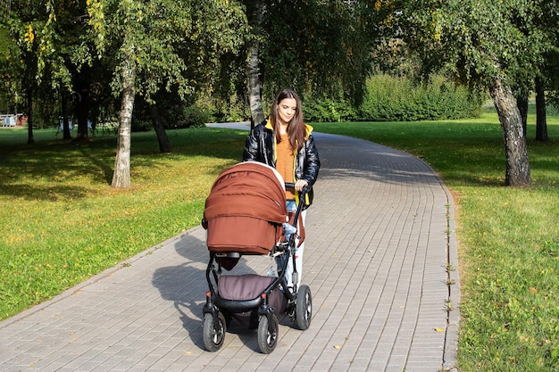 Uma garota com um carrinho caminha por um parque de outono