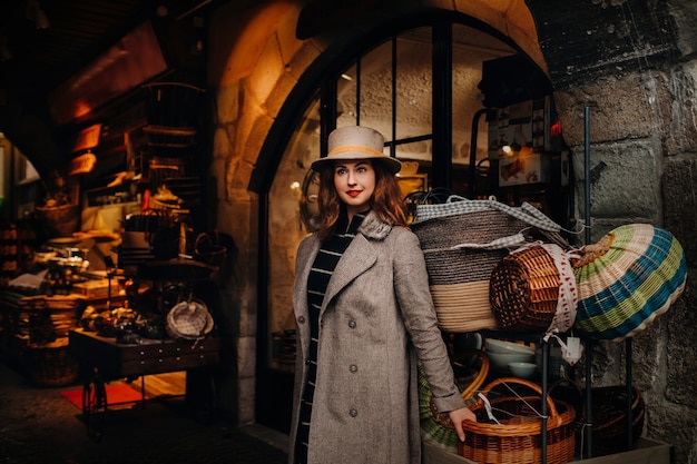 Uma garota com um casaco e um chapéu está perto de cestas na cidade velha de Annecy, passando um tempo ao ar livre explorando a cidade europeia