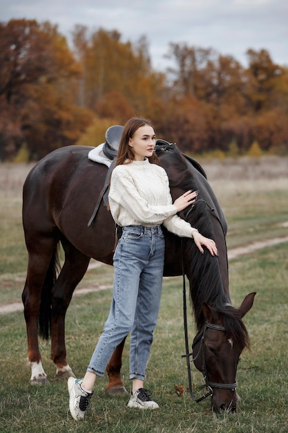 Uma garota com um cavalo na natureza, um passeio no outono com um animal