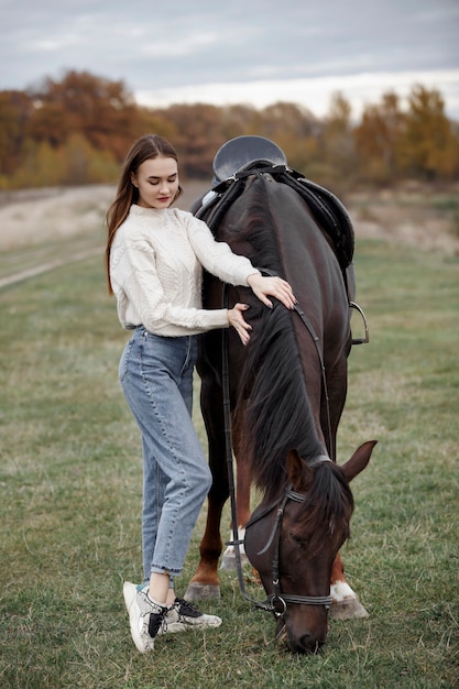 Uma garota com um cavalo na natureza, um passeio no outono com um animal
