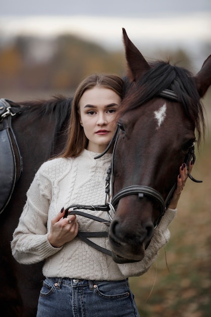 Uma garota com um cavalo na natureza, um passeio no outono com um animal