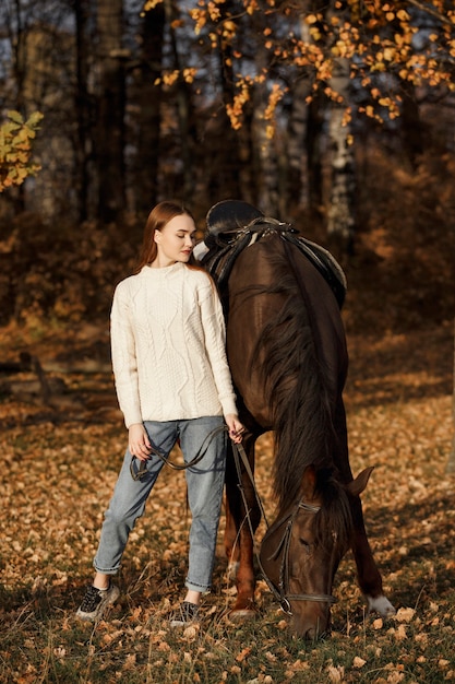 Uma garota com um cavalo na natureza, um passeio no outono com um animal