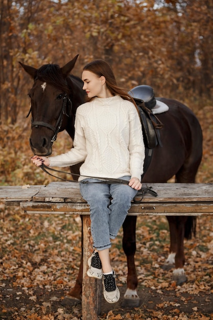 Uma garota com um cavalo na natureza, um passeio no outono com um animal