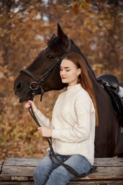 Uma garota com um cavalo na natureza, um passeio no outono com um animal