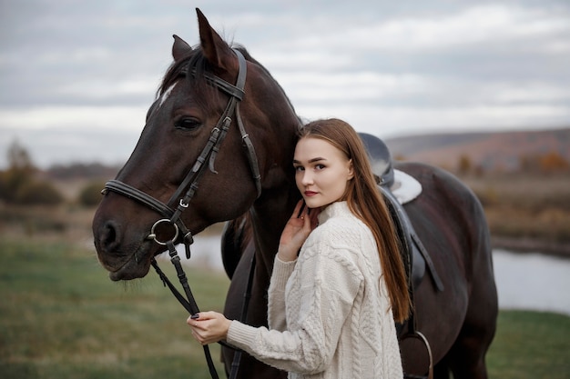 Uma garota com um cavalo na natureza, um passeio no outono com um animal