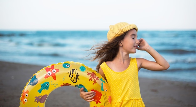 Uma garota com um círculo inflável amarelo à beira-mar Relaxando nas viagens de verão da praia