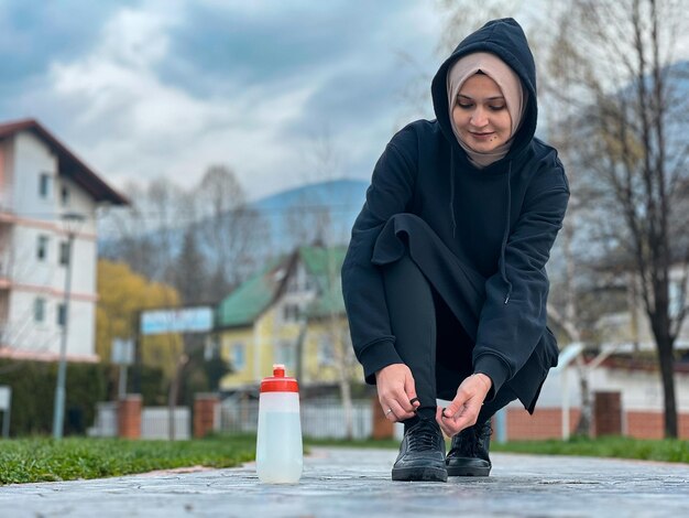 Uma garota com um hijab está se exercitando de manhã cedo Uma mulher muçulmana em roupas esportivas está se alongando ao ar livre