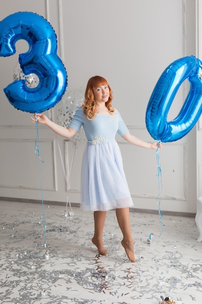 Foto uma garota com um número 30 azul e um balão azul